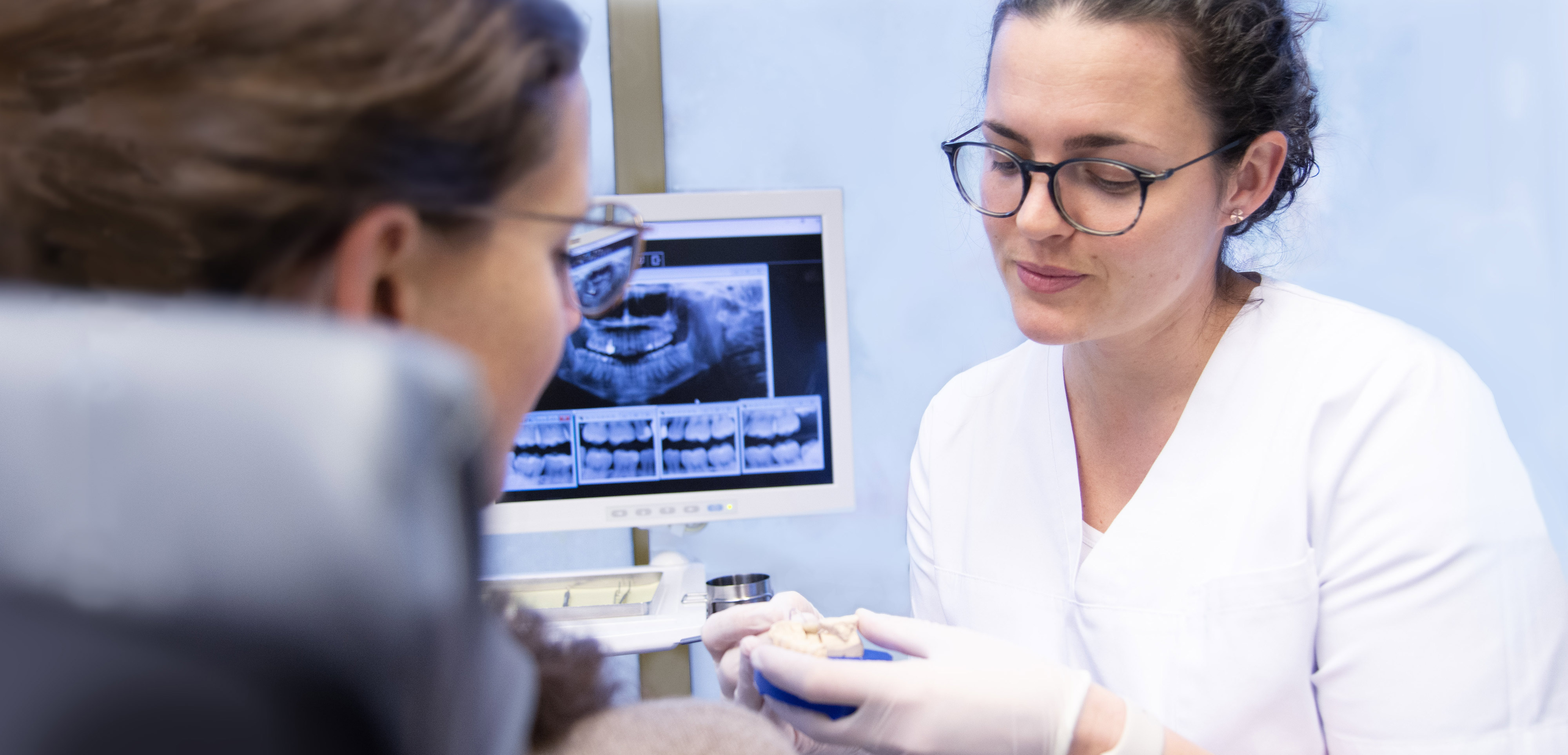 Zahnarztpraxis. Zahnärztin zeigt Patientin ein Gebiß.